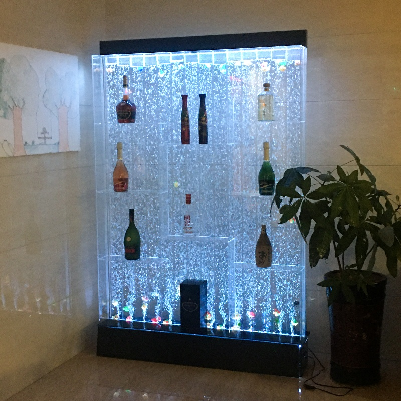 LED lighted display case with bottles inside, next to a plant.